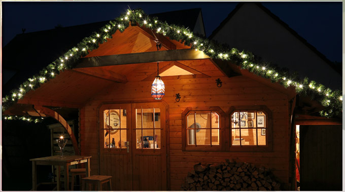 Gartenhaus mit von LED-Lichterkette beleuchteter Tannengirlande