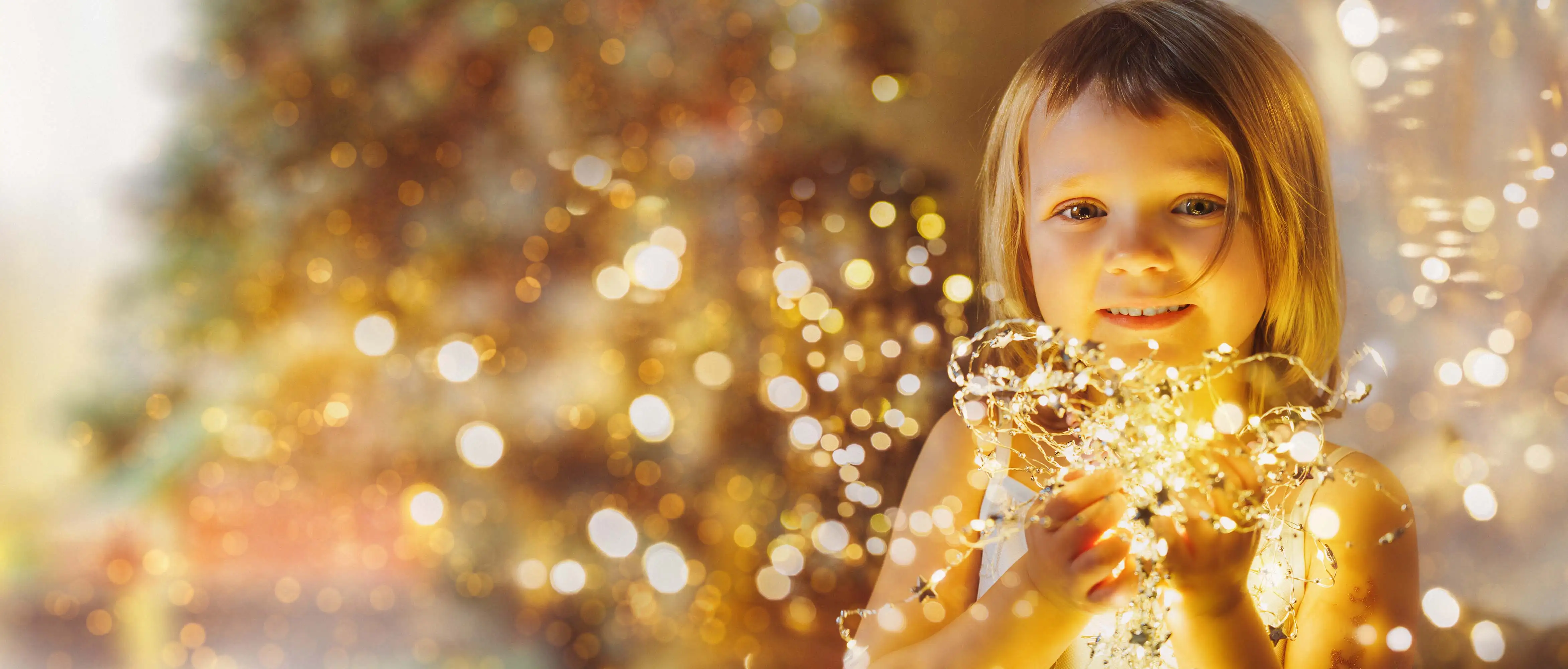 Ein Kind, das eine Lichterkette in der Hand hält.
