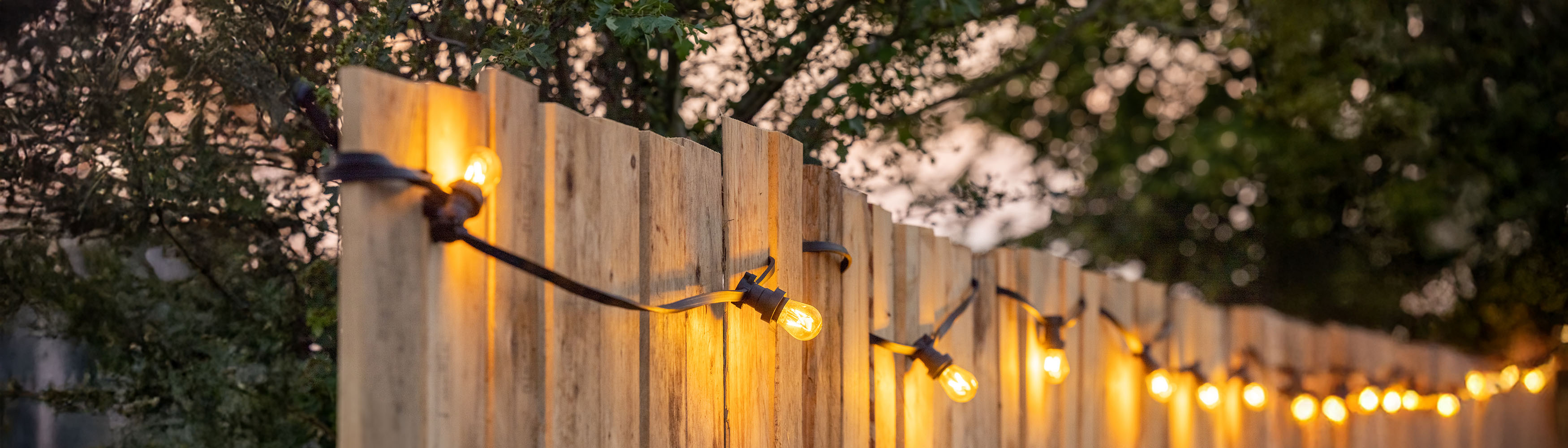 Holzzaun mit einer warmweißen Lichterkette