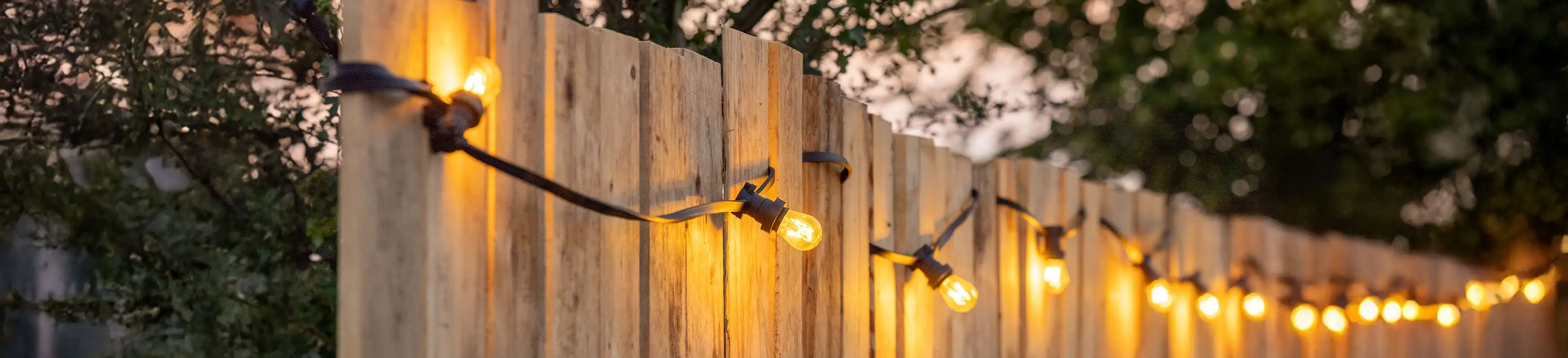 Holzzaun mit einer warmweißen Lichterkette